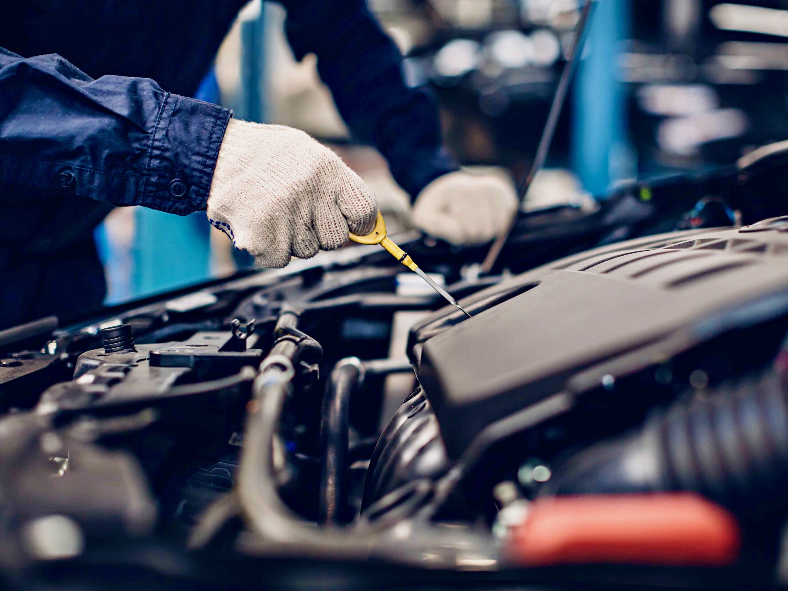 Auto car repair service center. Mechanic checking engine oil level